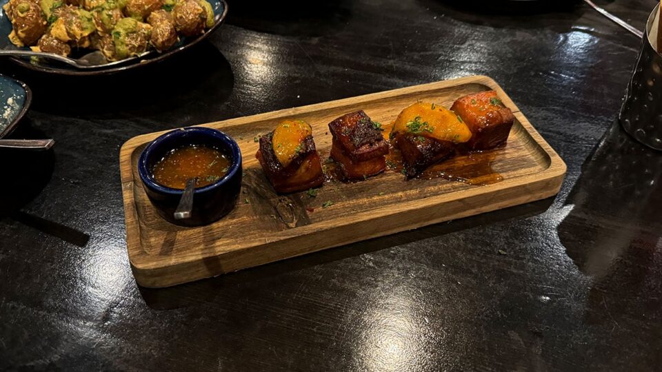 Smoked pork belly served with peach, grain mustard, and apricot sauce at Tres Social Tapas.