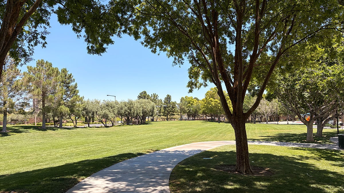 Walking path at North Tower Park in Summerlin surrounded by grass, trees, and mountain views.