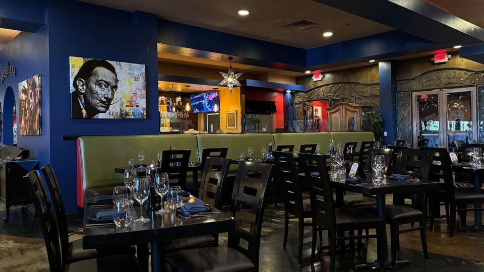 Interior dining room view of Tres Social Tapas featuring tables, artwork, and warm lighting.