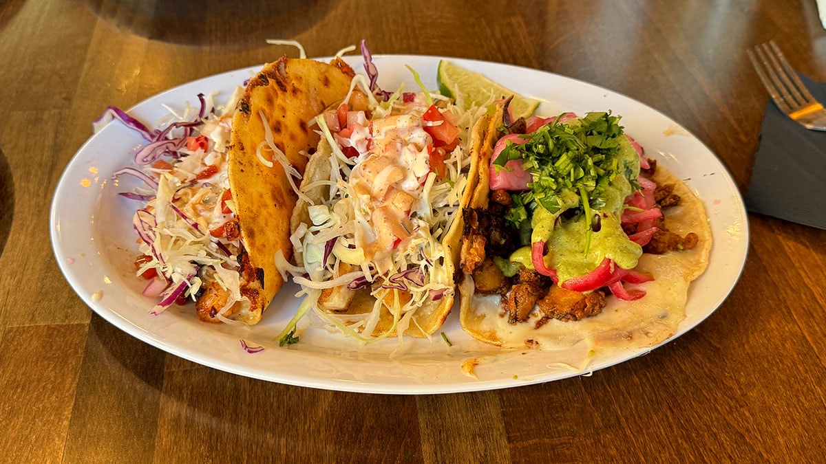 three Baja-style seafood tacos served with fresh toppings at Bajamar Seafood & Tacos
