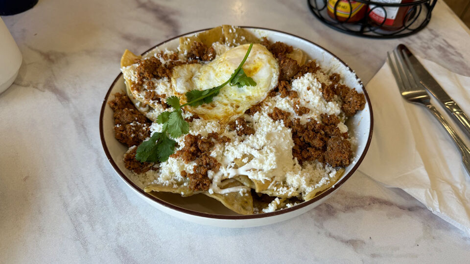 Chilaquiles Verde topped with crema, queso fresco, and a fried egg at The Morning News