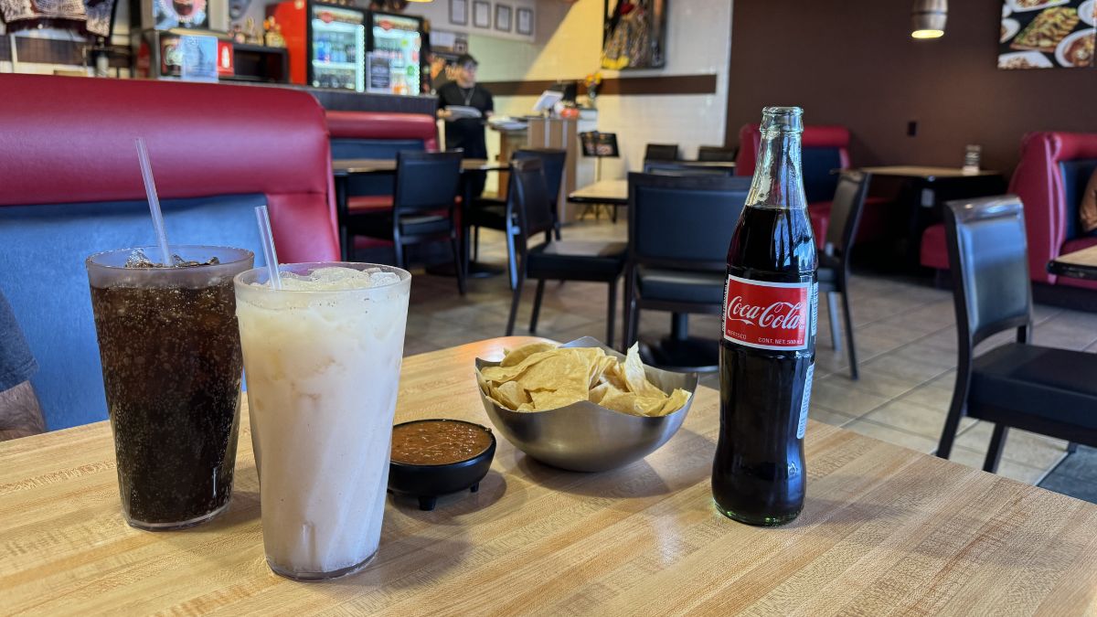 table with crispy tortilla chips and house salsa alongside a horchata and a glass bottle of Mexican Coke at Sin Fronteras Tacos y Más