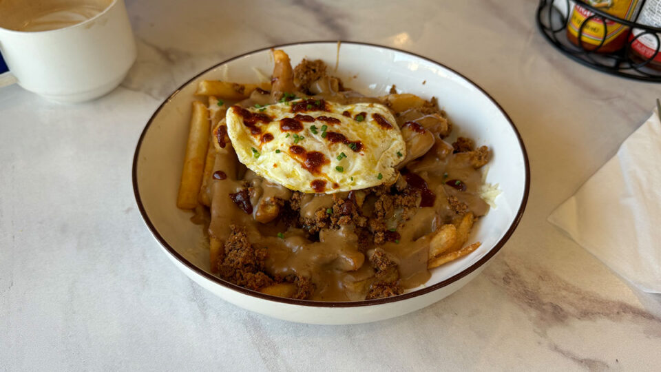 Chorizo Poutine with crispy fries, white cheddar, gravy, chorizo, and a fried egg