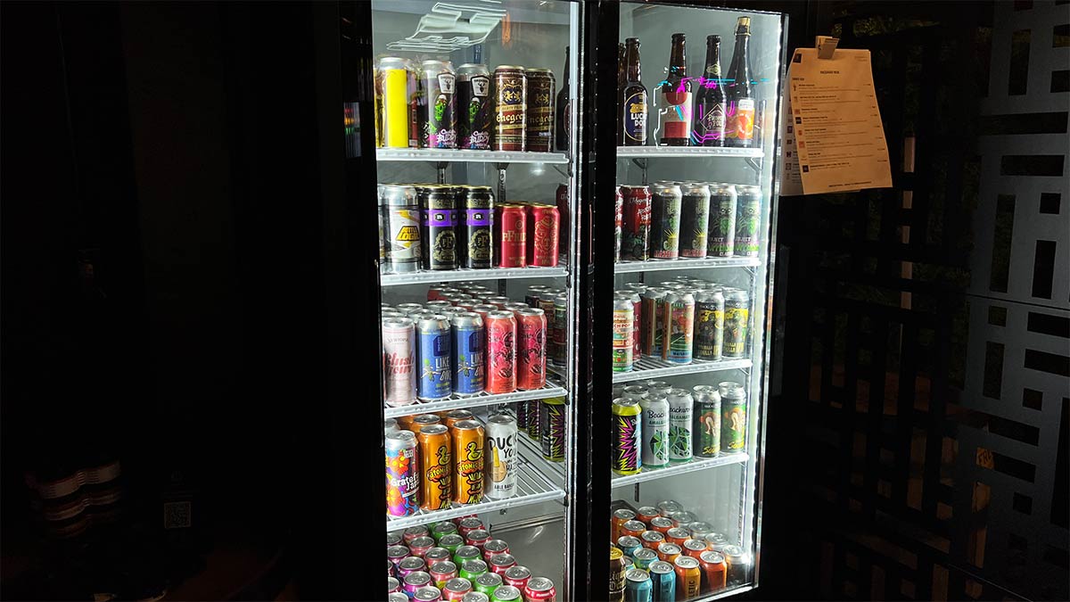Illuminated beer cooler filled with craft beer and canned drinks at Petrol Head Bar & Grill.