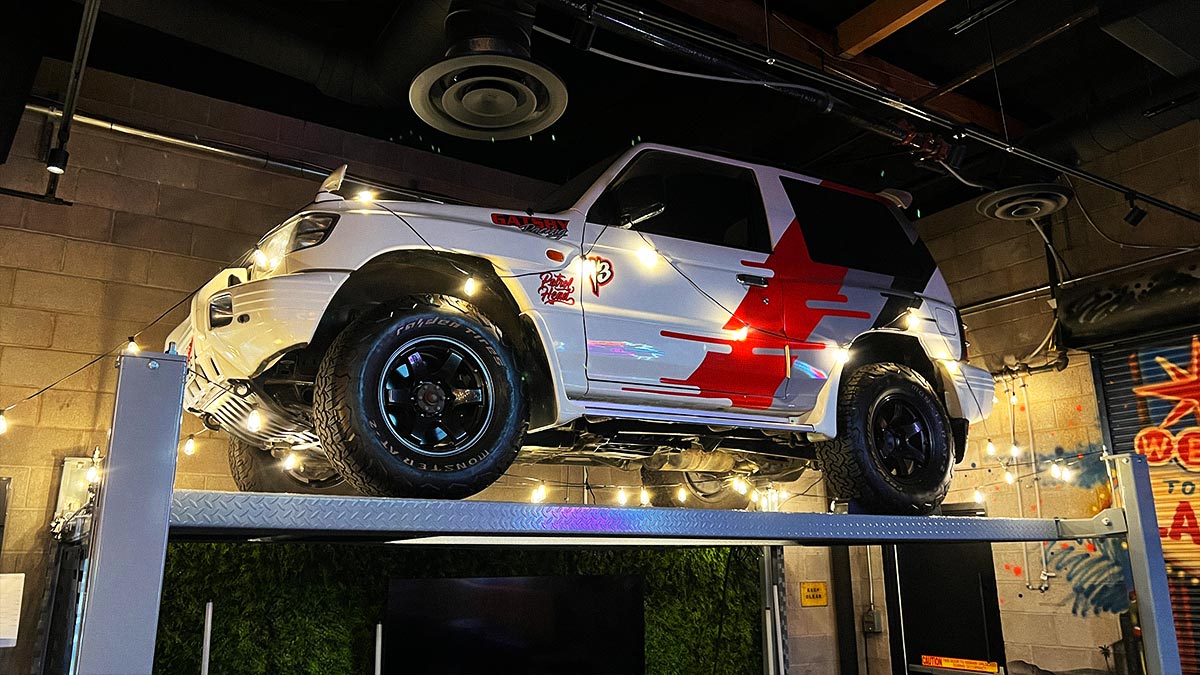 Mitsubishi Pajero Evolution displayed on a full car lift inside Petrol Head Bar & Grill.