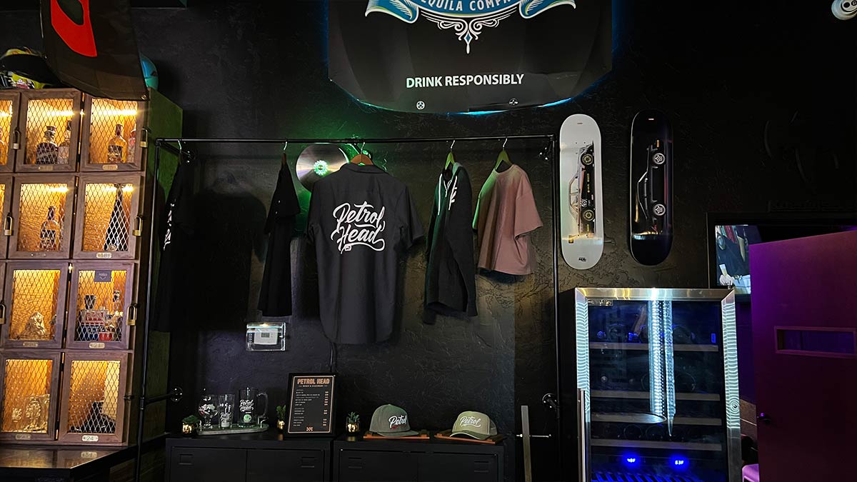 Petrol Head merchandise display with shirts, hats, glassware, and automotive skate decks.