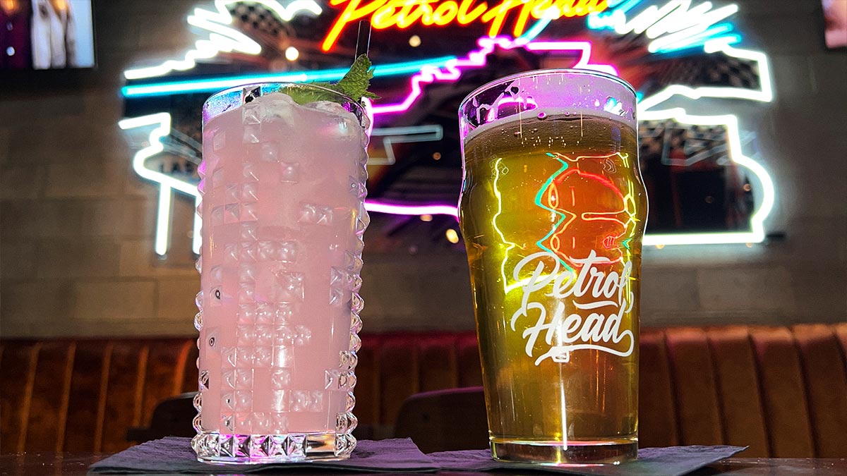 Pink Slip cocktail and Steve Austin’s Broken Skull 3:16 IPA in front of Petrol Head neon sign.