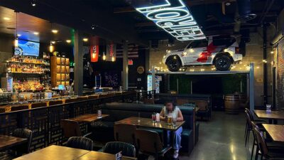 Booth seating, bar area, and elevated Mitsubishi Pajero Evolution inside Petrol Head Bar & Grill.