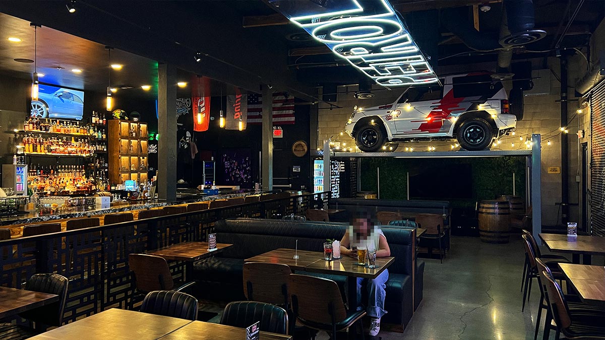 Booth seating, bar area, and elevated Mitsubishi Pajero Evolution inside Petrol Head Bar & Grill.