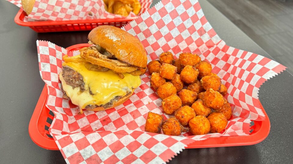 Smash burger served with crispy sweet potato tots at Chip Off the Block Deli.