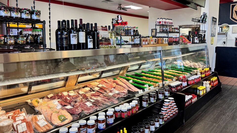 Bottles of wine and barbecue seasonings displayed beside fresh meat and poultry.