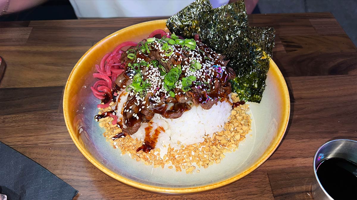 Bulgogi rice bowl with marinated beef, pickled red onion, garlic chips, sesame seeds, and nori.
