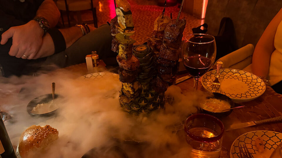 Beef and chicken kebabs with vegetables presented on skewers over a pineapple with dry ice at Marrakech Las Vegas.