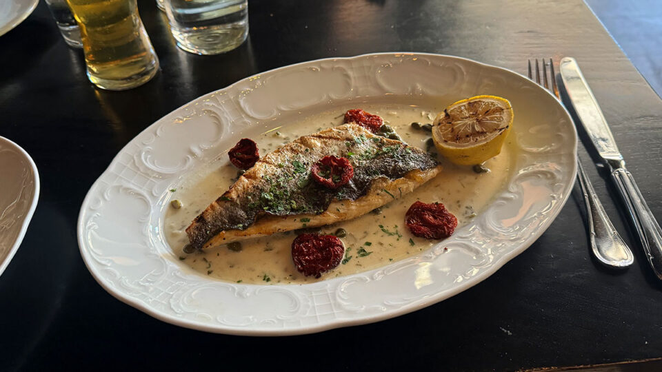 Branzino Piccata with lemon caper sauce, charred lemon, and confit tomato at Al Solito Posto