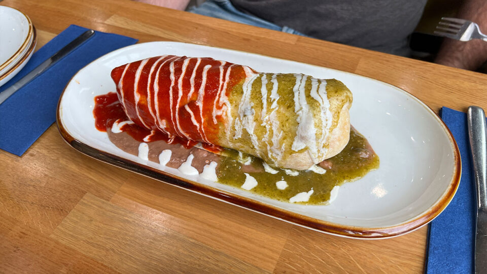 Wet Breakfast Burrito topped with sauce and sour cream at Good Morning Kitchen