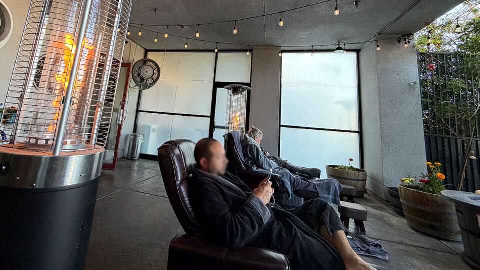 Guests relaxing in reclining chairs beneath string lights and patio heaters at The Spa at Lakeside in Las Vegas.