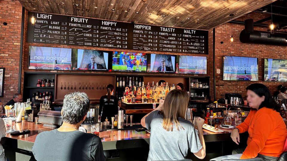 Large central bar with draft taps and televisions at Finney's Crafthouse