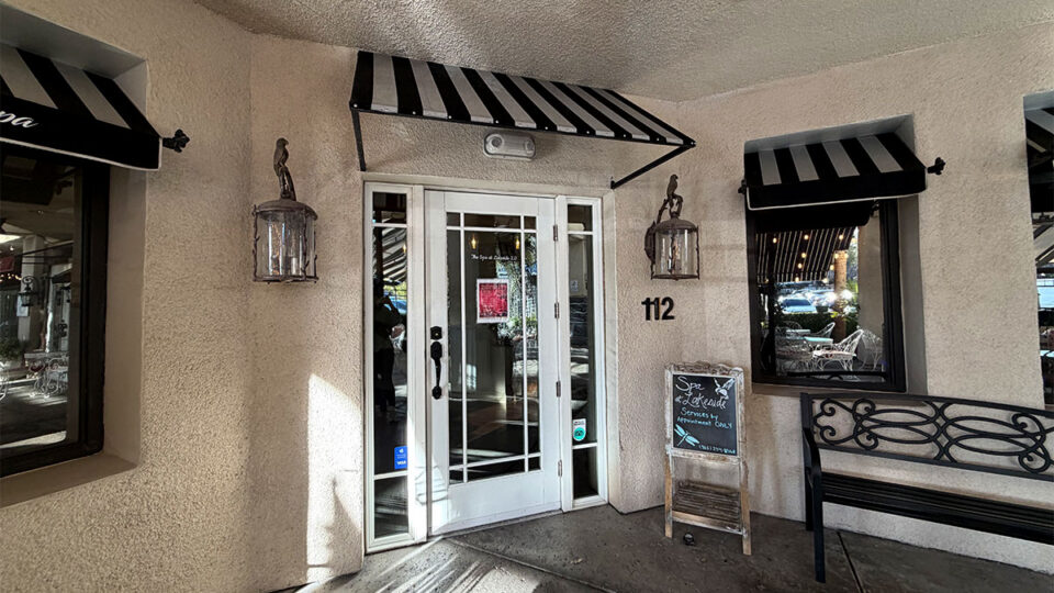 Front entrance to The Spa at Lakeside, Suite 112, with white glass doors, striped awnings, and an appointment-only sign.