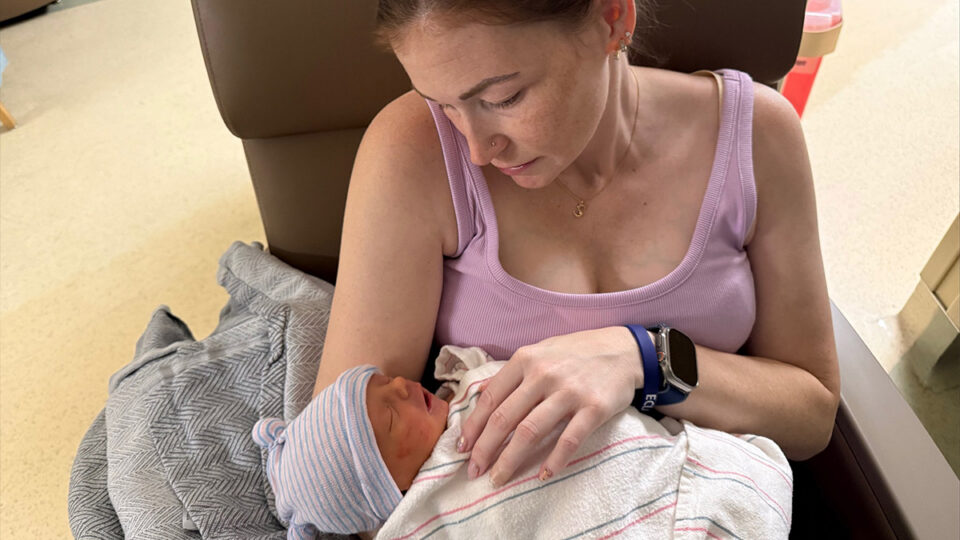 Phoebe London looking down at newborn Sullivan while holding him in the hospital